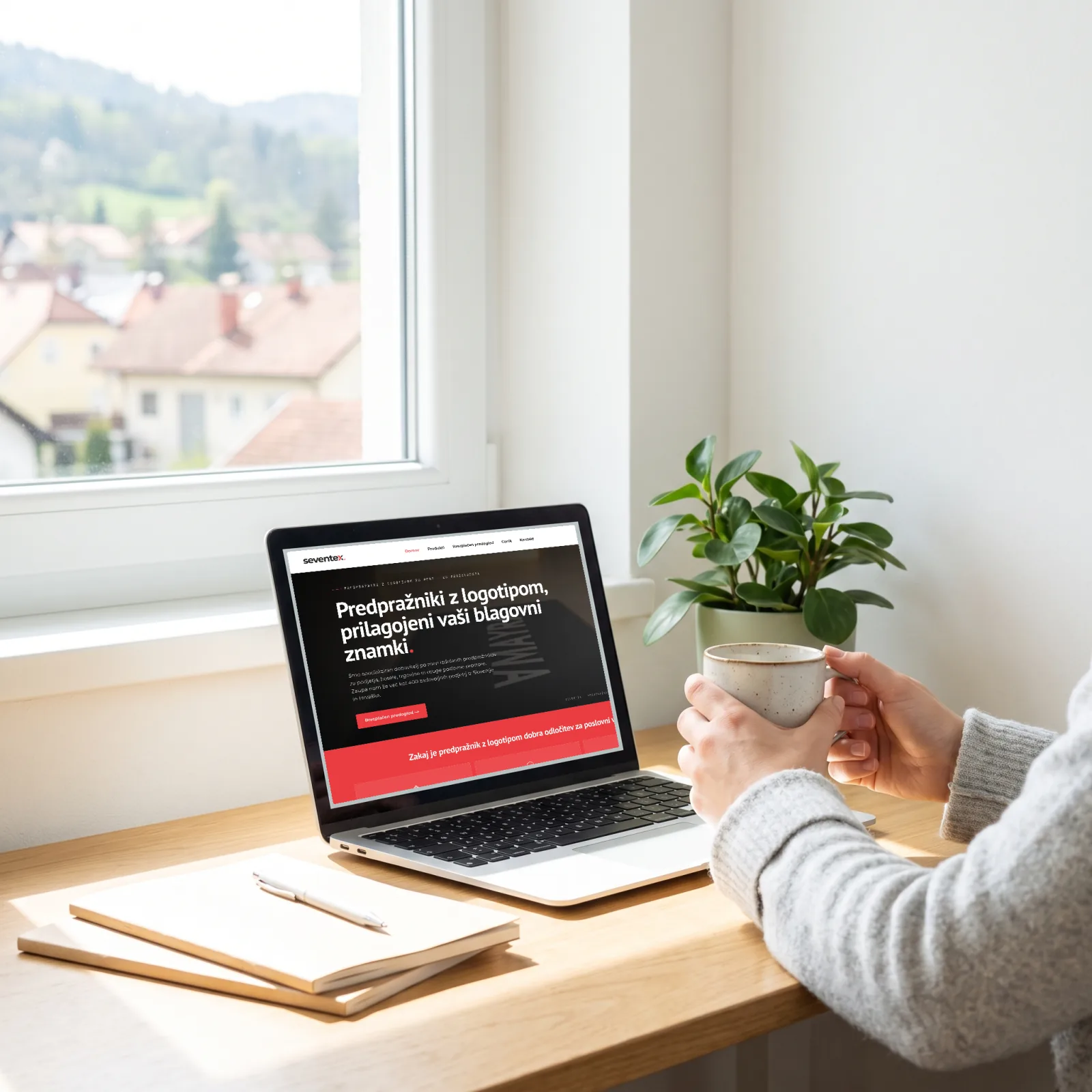 A laptop showing the Seventex website on a table by a window, hands holding a coffee cup nearby, with a village and hills outside